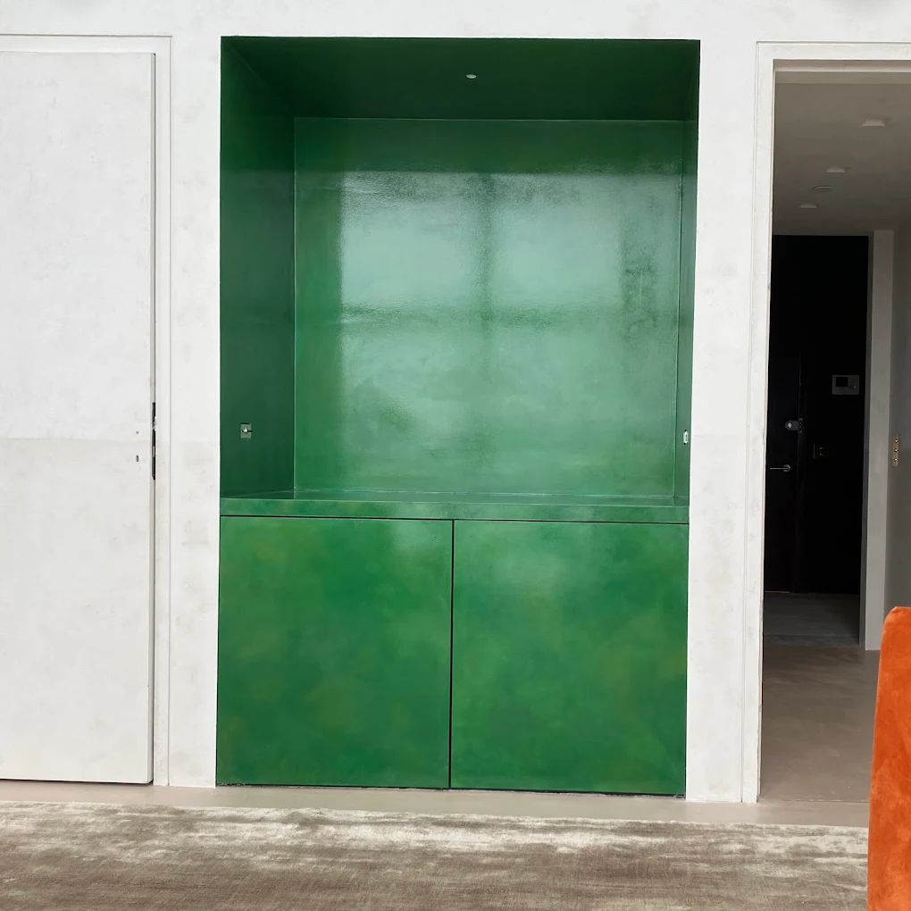 Emerald cabinetry wall set against pale mineral plaster.
